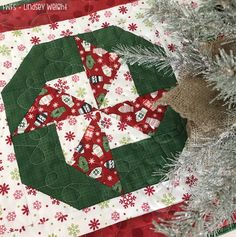 a green and red christmas ornament sitting on top of a quilted table runner