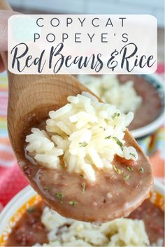 a spoon full of red beans and rice is being held up over a bowl filled with white rice