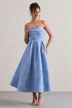 a woman in a strapless blue dress poses for the camera with her hands on her hips