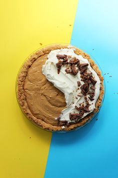 a pie with white frosting and chocolate shavings on top, sitting on a blue and yellow table