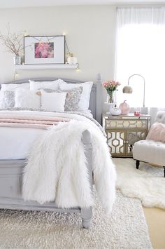 a bedroom with a bed, chair and pictures on the wall above it is decorated in white fur