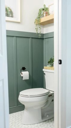 a white toilet sitting inside of a bathroom next to a green paneled wall and floor