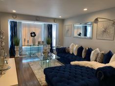 a living room filled with blue couches and white pillows on top of a hard wood floor