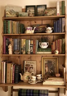 a book shelf filled with lots of books and teapots on top of it