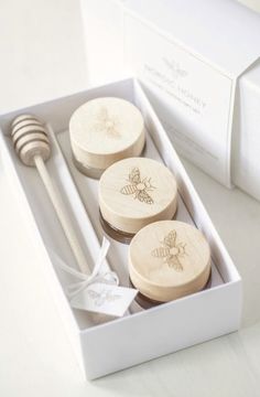 three wooden spoons in a white box next to a honey dipper and fork