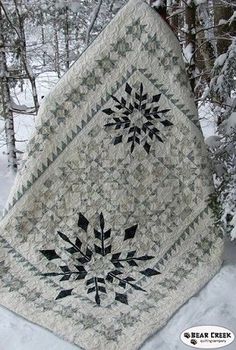 a quilt is hanging from a tree in the snow