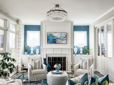 a living room filled with furniture and a chandelier above a fire place in front of a fireplace