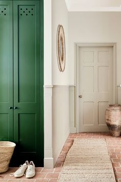 a dog laying on the floor in front of a green door and some white walls