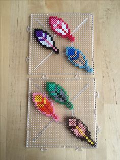 four pieces of perler bead art sitting on top of a wooden table next to each other