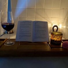 an open book sitting on top of a table next to a glass of wine