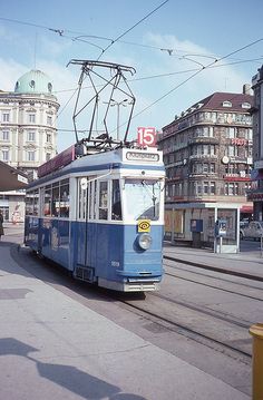 a blue and white trolley on tracks near buildings