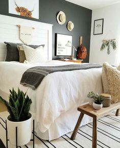 a bed room with a neatly made bed next to a plant and pictures on the wall