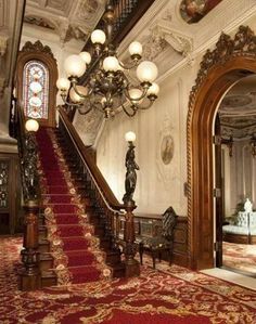 an ornate staircase with red carpet and chandelier