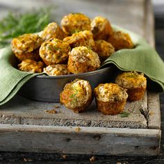 a metal bowl filled with meatballs on top of a wooden table next to a green napkin