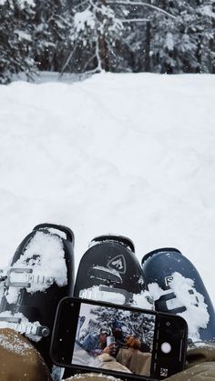 two snowboarders are sitting in the snow with their feet propped up and taking a photo