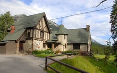 a large house sitting on the side of a road next to a lush green forest