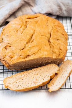 a loaf of bread sitting on top of a cooling rack next to a slice of bread