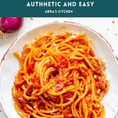 a white plate filled with spaghetti and sauce on top of a table next to garlic