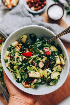 a person holding a white bowl filled with salad