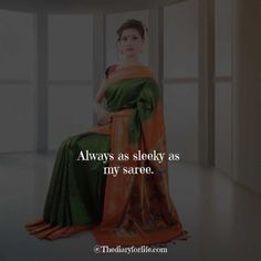 a woman in green and orange saree sitting on the floor with her hand on her hip