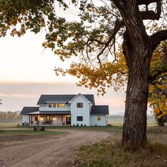 a large white house sitting on top of a lush green field next to a tree