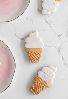 three ice cream cookies sitting on top of a white counter next to plates and bowls