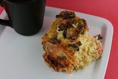 a white plate topped with two pieces of food next to a black cup on top of a red table