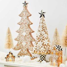 three wooden christmas trees sitting on top of a white shelf next to other ornaments and decorations