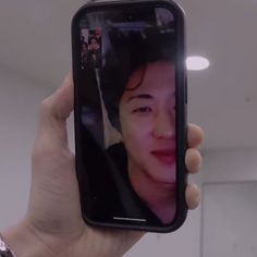 a person holding up a cell phone with an image of a man's face on it