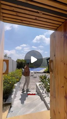 a person standing in front of a wooden structure and looking at the camera through an open door