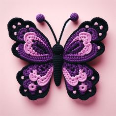 a crocheted purple and black butterfly on a pink background