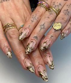 two hands with gold and white nail designs on them