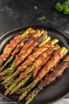 asparagus wrapped in bacon on a black plate