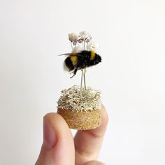 a tiny bee sitting on top of a piece of grass with flowers growing out of it