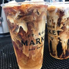 two drinks sitting next to each other on top of a black table with white writing