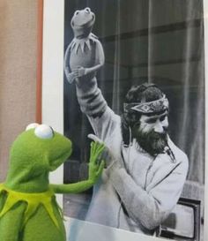 kermie the frog holding up a stuffed animal in front of a poster that says, james may tim horton