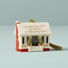 a ceramic house ornament with a tassel hanging from it