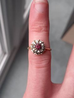 A vintage 18ct gold ruby and diamond ring. The ring is not Hallmarked but it has been tested as 1ct gold. The 3 x 3mm round cut ruby is claw set at the centre of the ring. This is surrounded by 10 round brilliant cut diamonds. The total diamond weight is 0.20ct's, and in our opinion the colour of the diamonds is an H/I, with a SI1 clarity. Finger size H, but we can make this ring bigger, or smaller. Red Ruby Cluster Ring With Rose Cut Diamonds, Red Cluster Ring With Rose Cut Diamonds, Antique Ruby Ring With Single Cut Diamonds, Red Diamond Birthstone Ring With Rose Cut, Red Diamond Cluster Ring With Rose Cut, Cluster Ruby Ring With Rose Cut Diamonds, Red Cluster Ring Stamped 14k, Red 14k Stamped Cluster Ring, Vintage Ruby Rings With Single Cut Diamonds