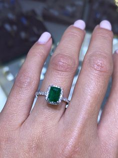 a close up of a person's hand with a ring on their finger and an emerald stone in the middle