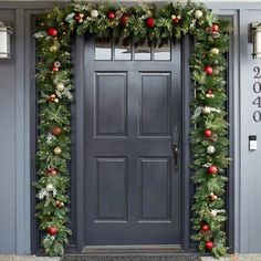 a front door decorated for christmas with greenery and ornaments on the outside, along with lights