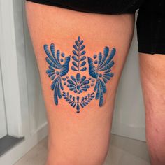 a woman's thigh with a blue tattoo design on it