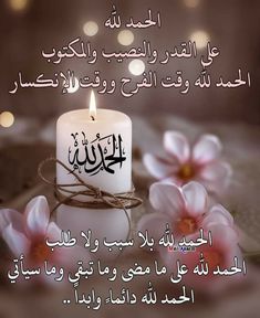 a lit candle with arabic writing on it and flowers in the foreground, against a blurred background