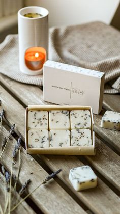 a box of soaps sitting on top of a wooden table next to a candle