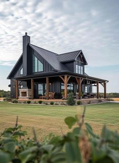 a large black house sitting on top of a lush green field