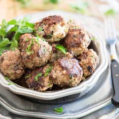 a bowl filled with meatballs and garnished with herbs