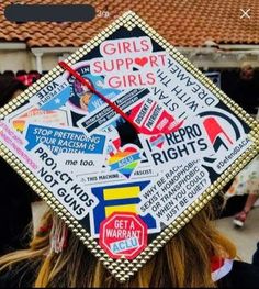 a girl wearing a graduation cap with stickers on it's back and the words girls support girls