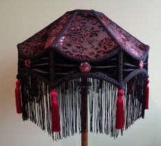 a lamp shade with tassels and beads on it sitting on a wooden stand