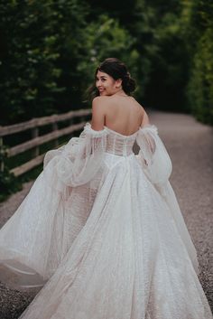 a woman in a white dress is walking down the road with her back to the camera