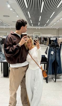 a man and woman taking a selfie in a clothing store