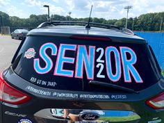 the back end of a car that has been decorated with pink, blue and white letters